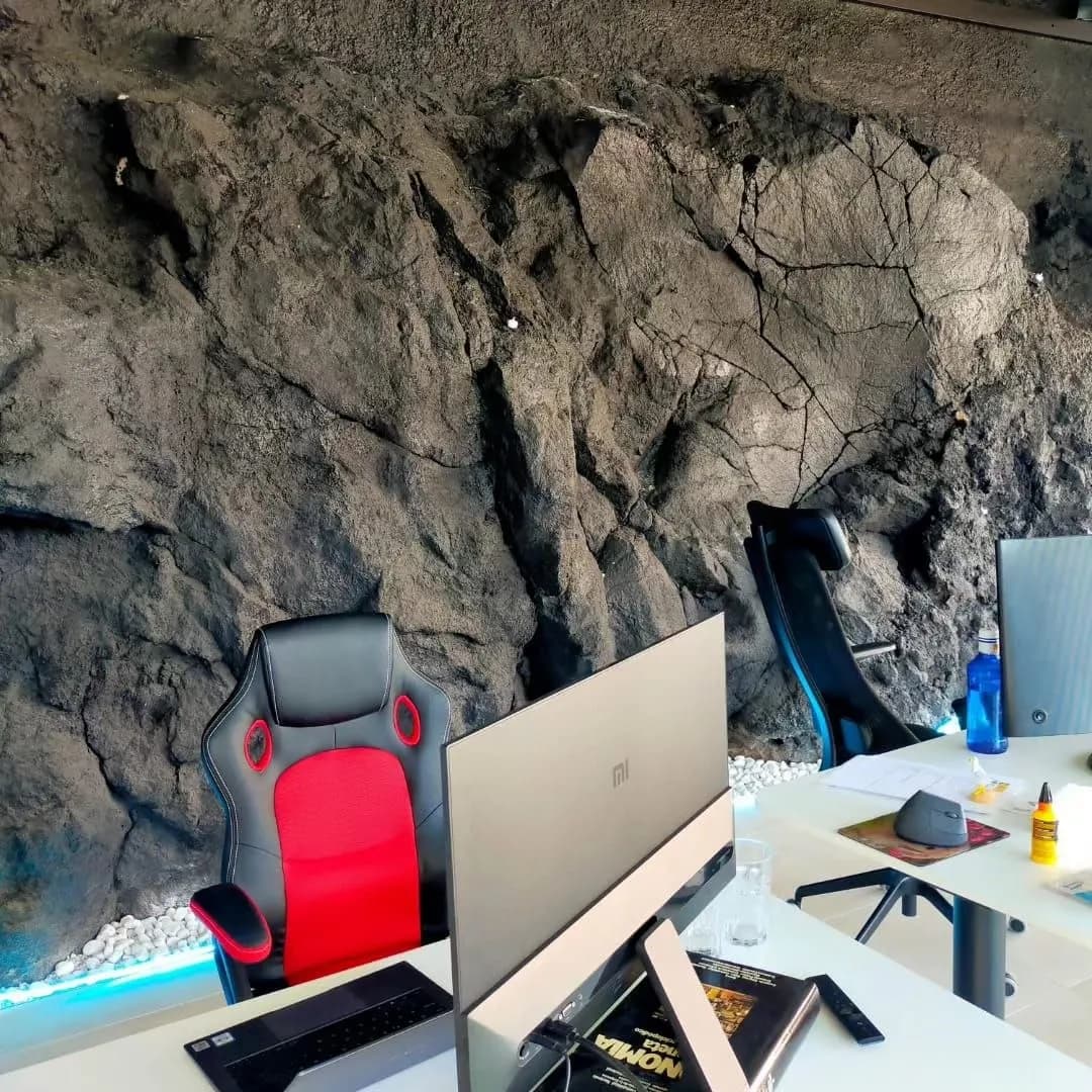 Indoor coworking space with a volcanic rock wall.