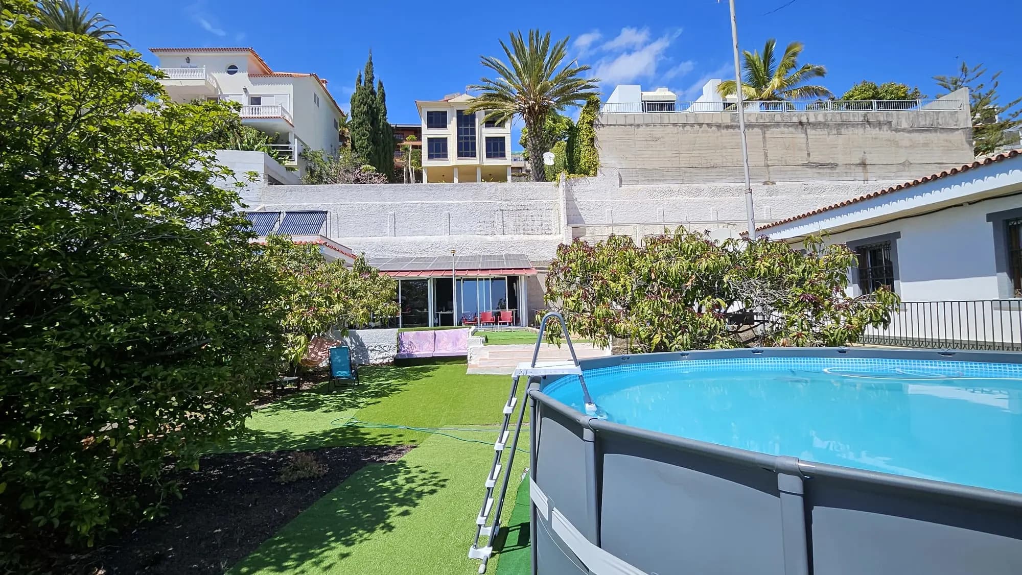 Blue Paradise pool terrace with loungers and garden views.