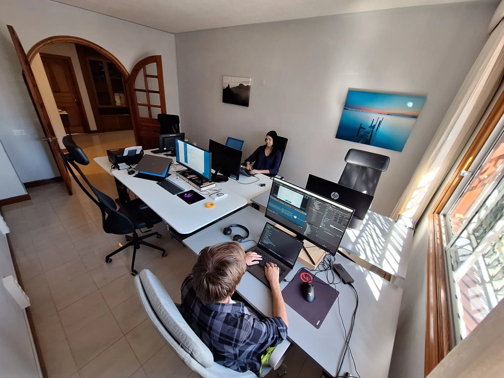 Indoor coworking area with desks, monitors, and garden views.