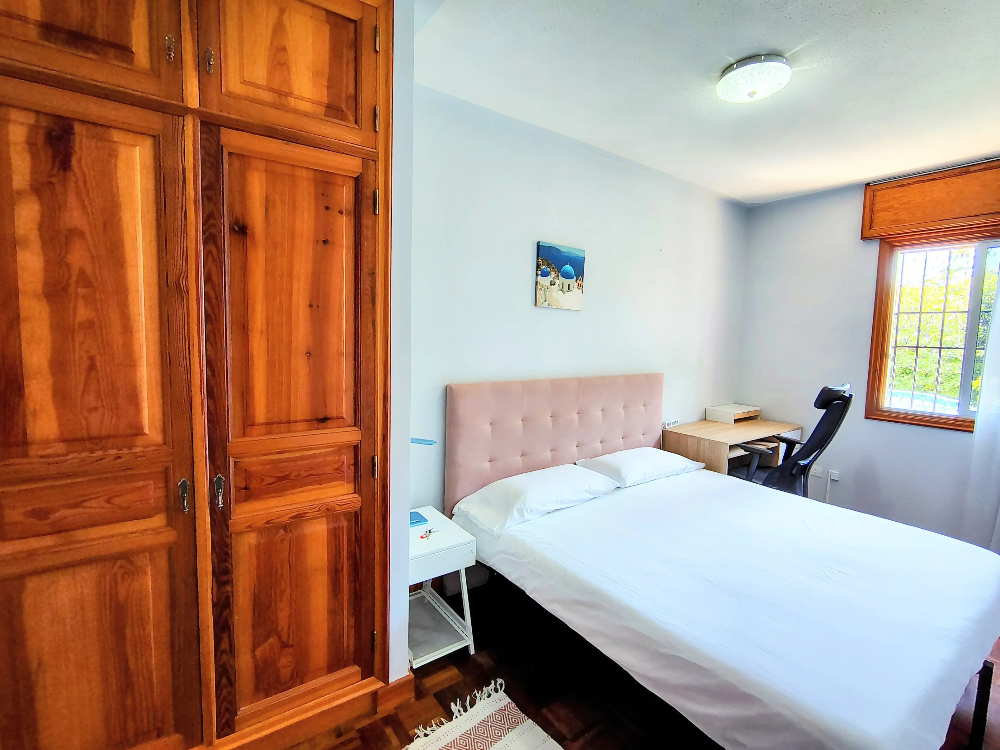 Comfortable private room with bed, storage, desk, and natural light at Blue Paradise.
